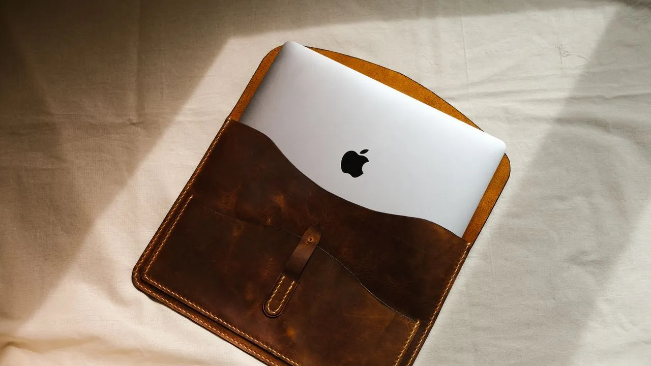 Laptop being slid into a protective sleeve case on a fabric surface
